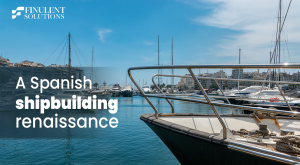 A marina in Spain with luxury yachts docked along the waterfront under a clear blue sky. The bow of a yacht dominates the foreground, with city buildings and masts in the background. Overlay text reads, "A Spanish shipbuilding renaissance," alongside the Finulent Solutions logo.